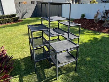 Outdoor Cat Tower on a grassy area with a house and fence in the background